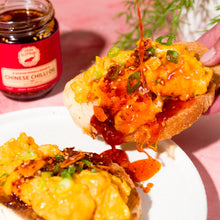 Load image into Gallery viewer, Two slices of bread topped with a yellow spread and green onions, with a jar of Chinese chilli sauce in the background.