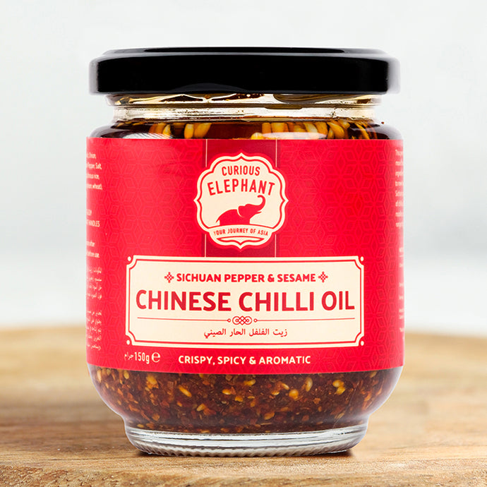 Jar of Curious Elephant Chinese Chilli Oil on a wooden surface with a white background