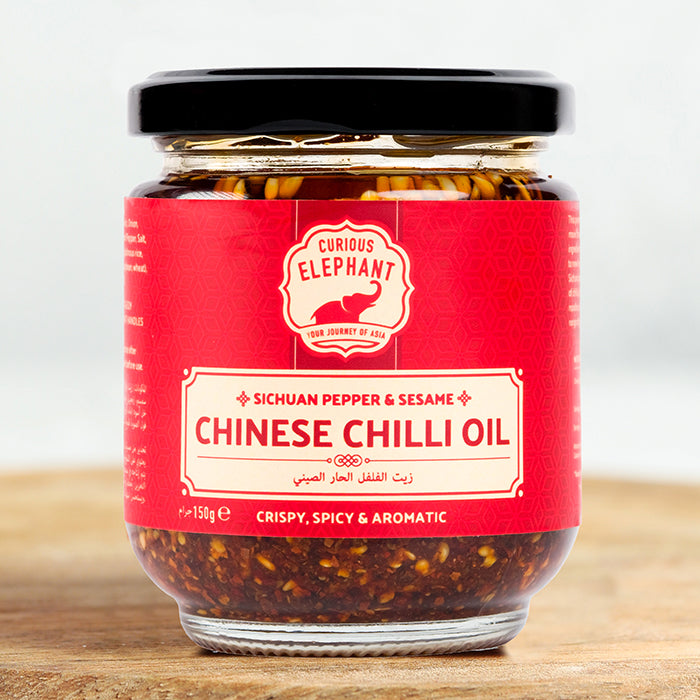 Jar of Curious Elephant Chinese Chilli Oil on a wooden surface with a white background